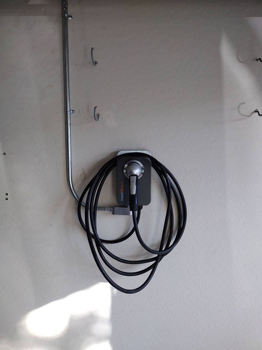 ChargePoint home charger fed by conduit on a garage wall